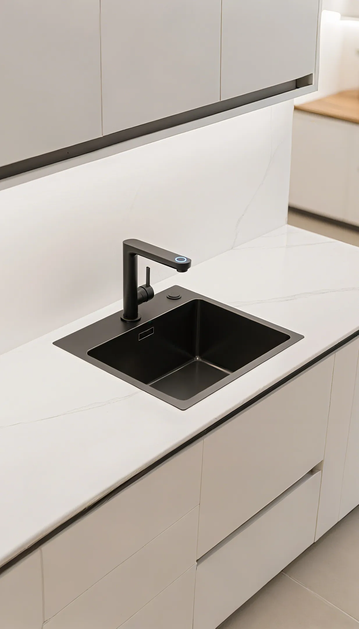 Minimalist black kitchen island with rectangular stainless steel sink, silver faucet, bright windows, white walls, and small plant decoration